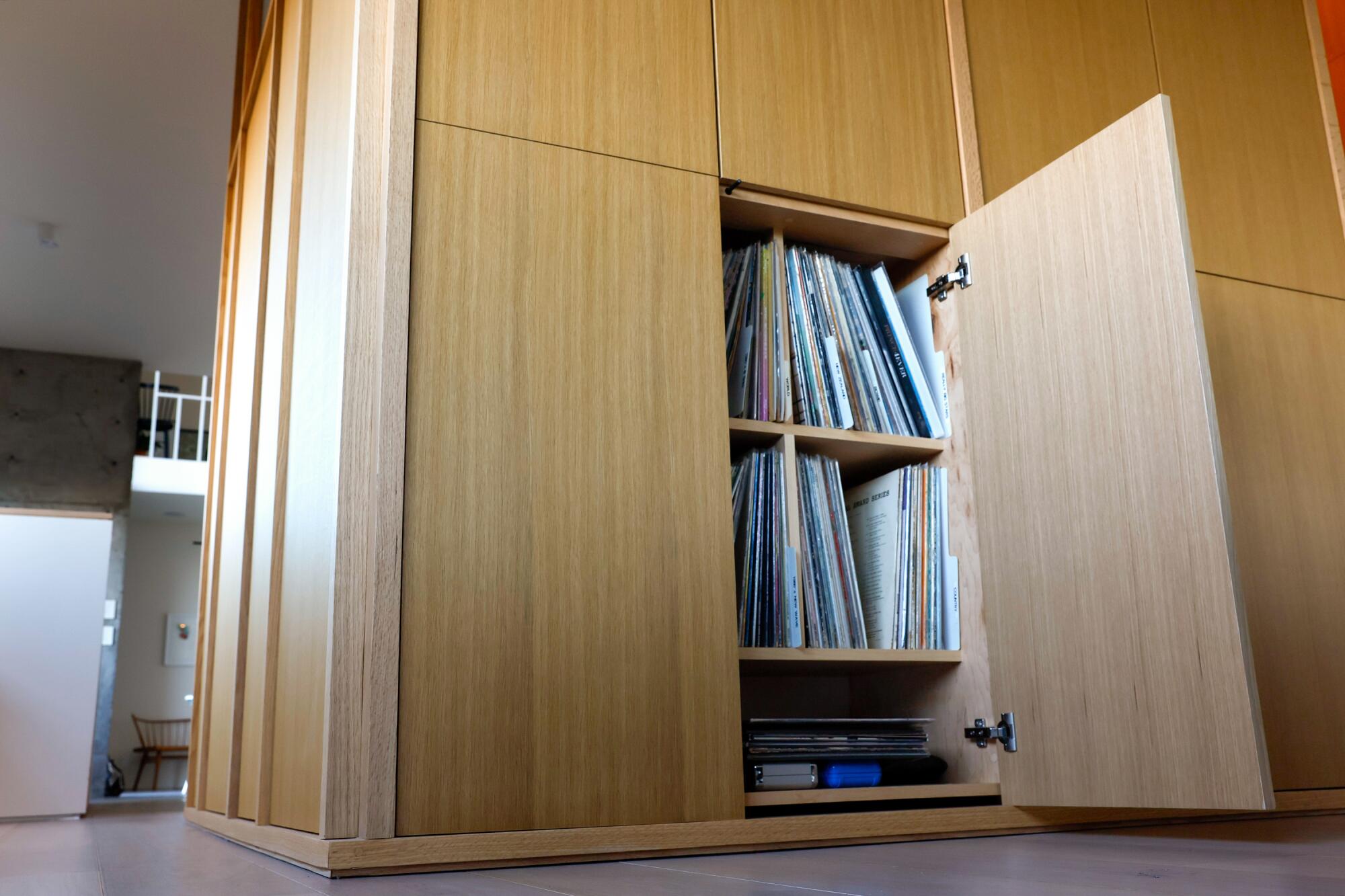 Records are hidden behind light wood cabinets that look hidden in the walls. 