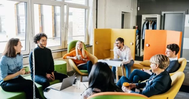 קבוצת עובדים עסקיים יושבים יחד ועורכים סיעור מוחות של אסטרטגיית חווית עובדים במהלך פגישה במשרד.