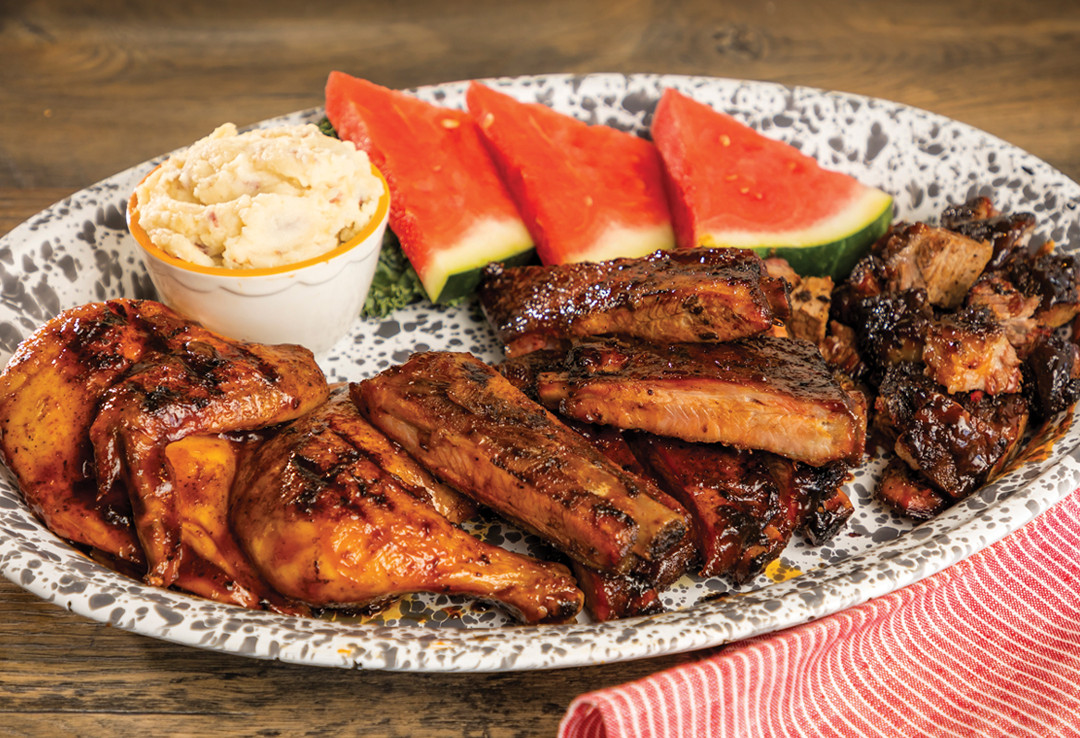 dish with pieces of ribs and chicken with watermelon and toppings at Lucille's BBQ menu