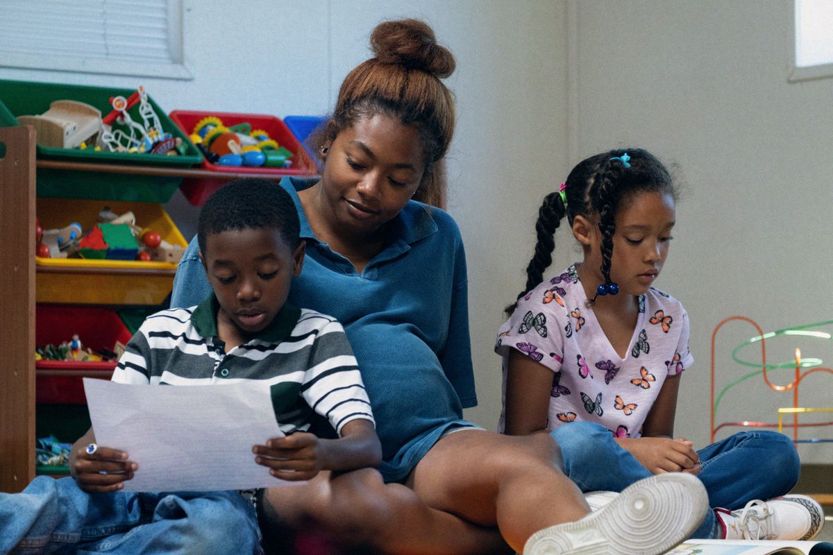 Беременная женщина (Тиа Номор) сидит на полу с двумя маленькими детьми, пока они читают и играют в «Мама Земли».