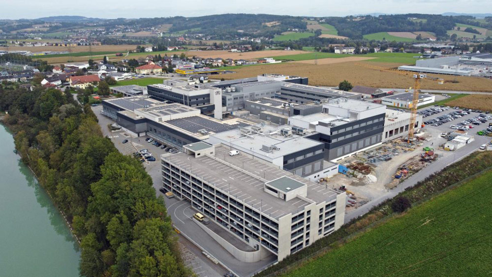 Aerial view of EVG’s corporate HQ in St. Florian, Austria. In the foreground are the completed Manufacturing IV and V buildings, as well as the Manufacturing VI building, which is under construction. Source: EVG.
