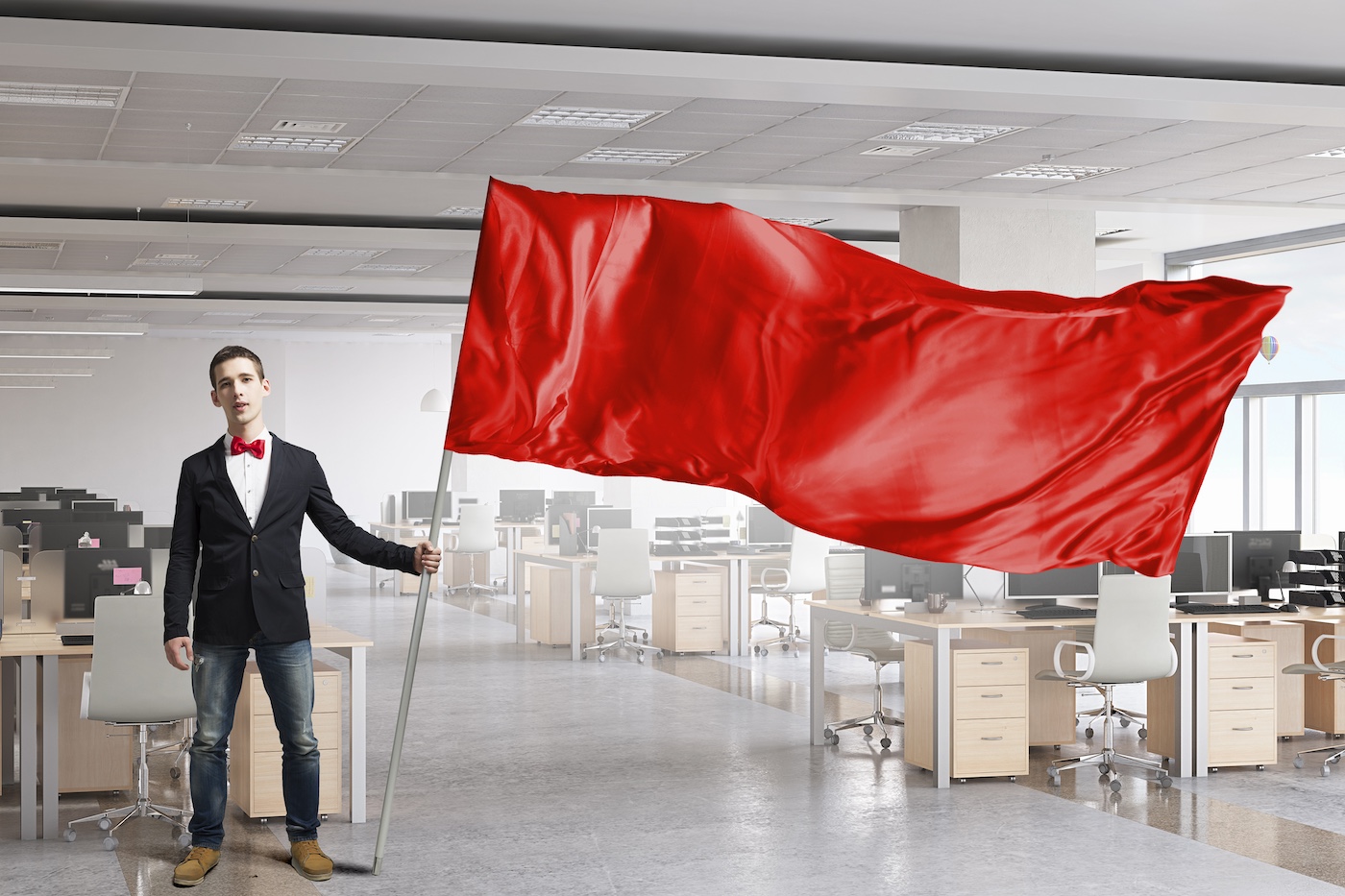 Uomo che sventola bandiera rossa in guardia da un'azienda tecnologica vuota