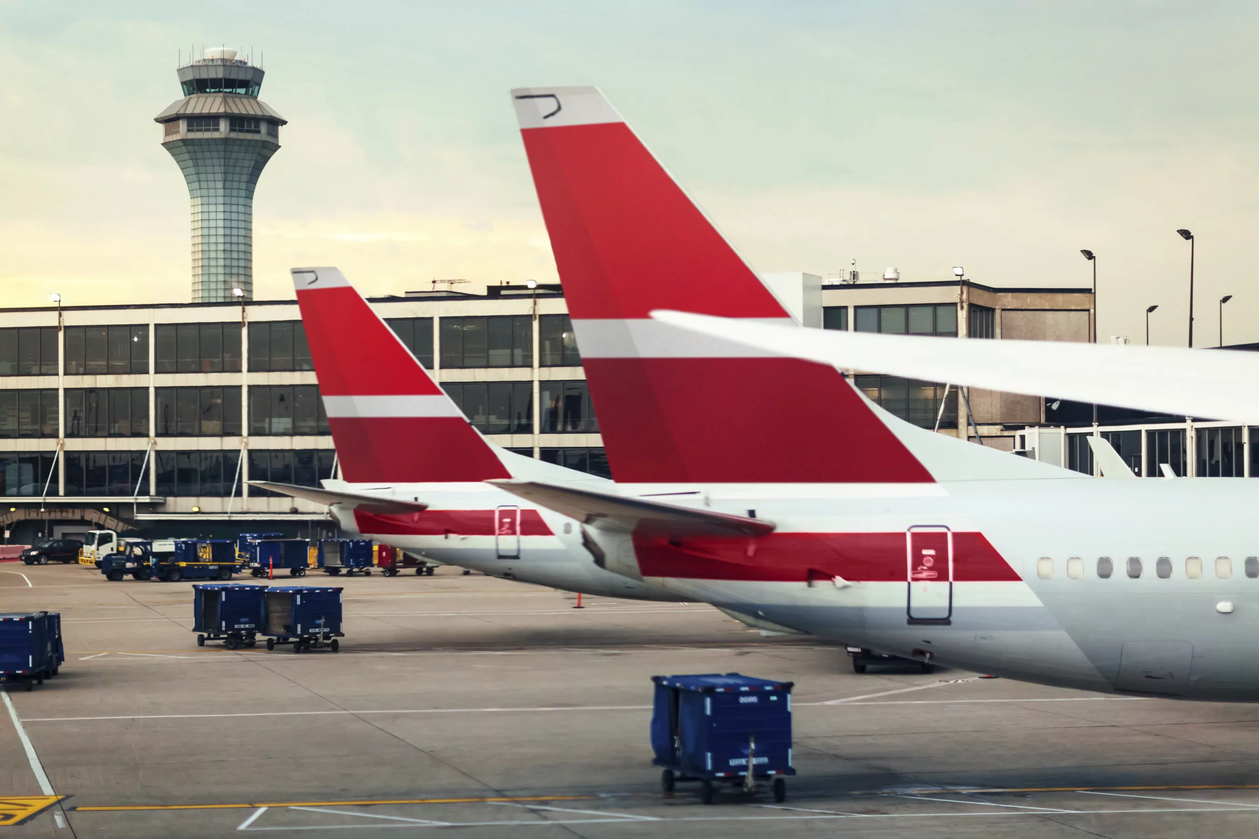 Two airplane tails on tarmac at airport