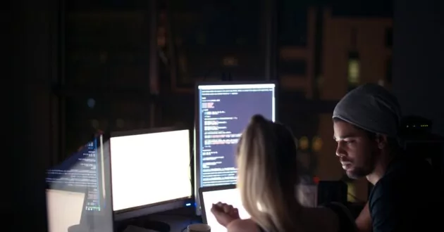 two people at a computer at night safeguarding systems from hackers