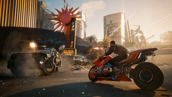 Uno screenshot dell'espansione Phantom Liberty di Cyberpunk 2077 che mostra il giocatore che corre per le strade della città su una motocicletta rossa mentre un veicolo blindato apre il fuoco davanti a sé.
