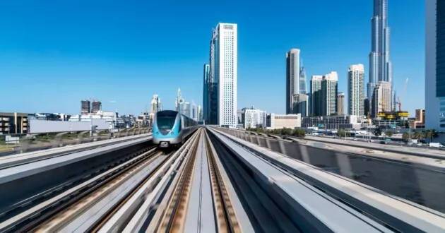 Združeni arabski emirati, Dubaj, pogled iz notranjosti vlaka, ki se pelje po tirih v sistemu javnega prevoza dubajske podzemne železnice z obzorjem središča mesta v daljavi.