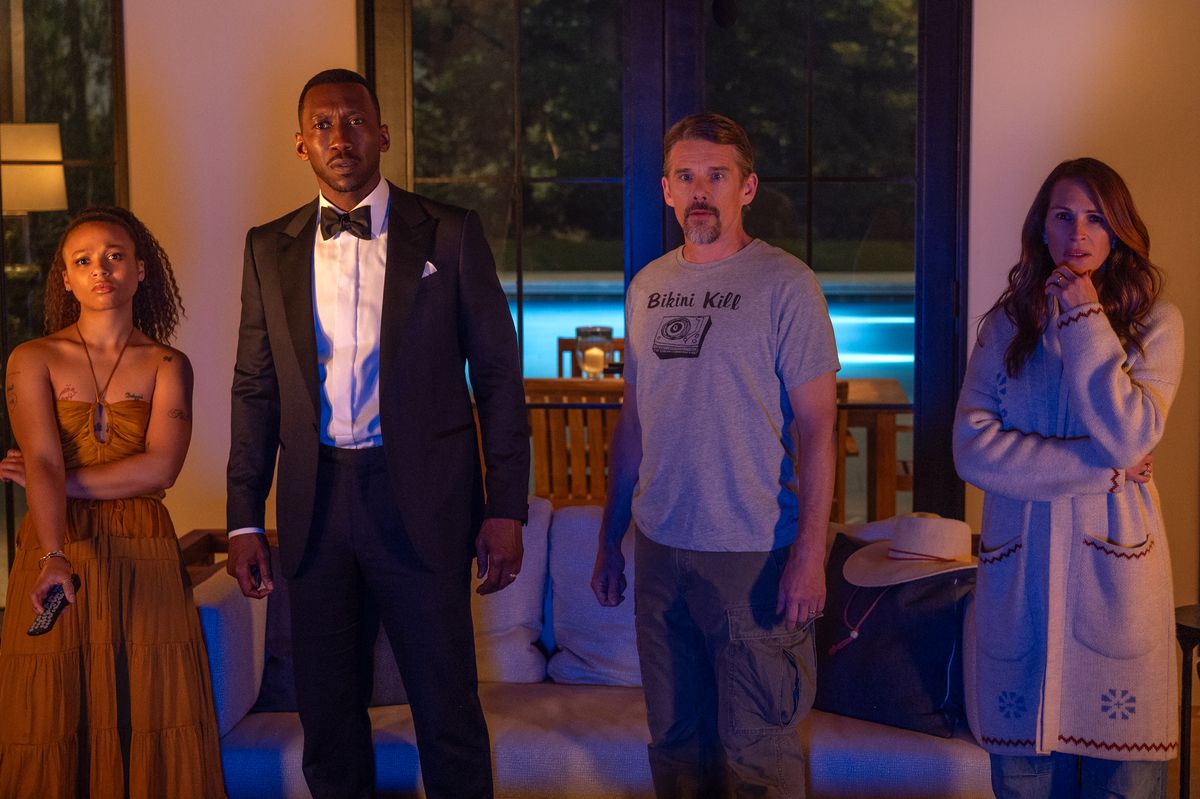Myha’la, Mahershala Ali, Ethan Hawke, and Julia Roberts stand next to each other and stare at a TV worried in the Netflix film Leave the World Behind