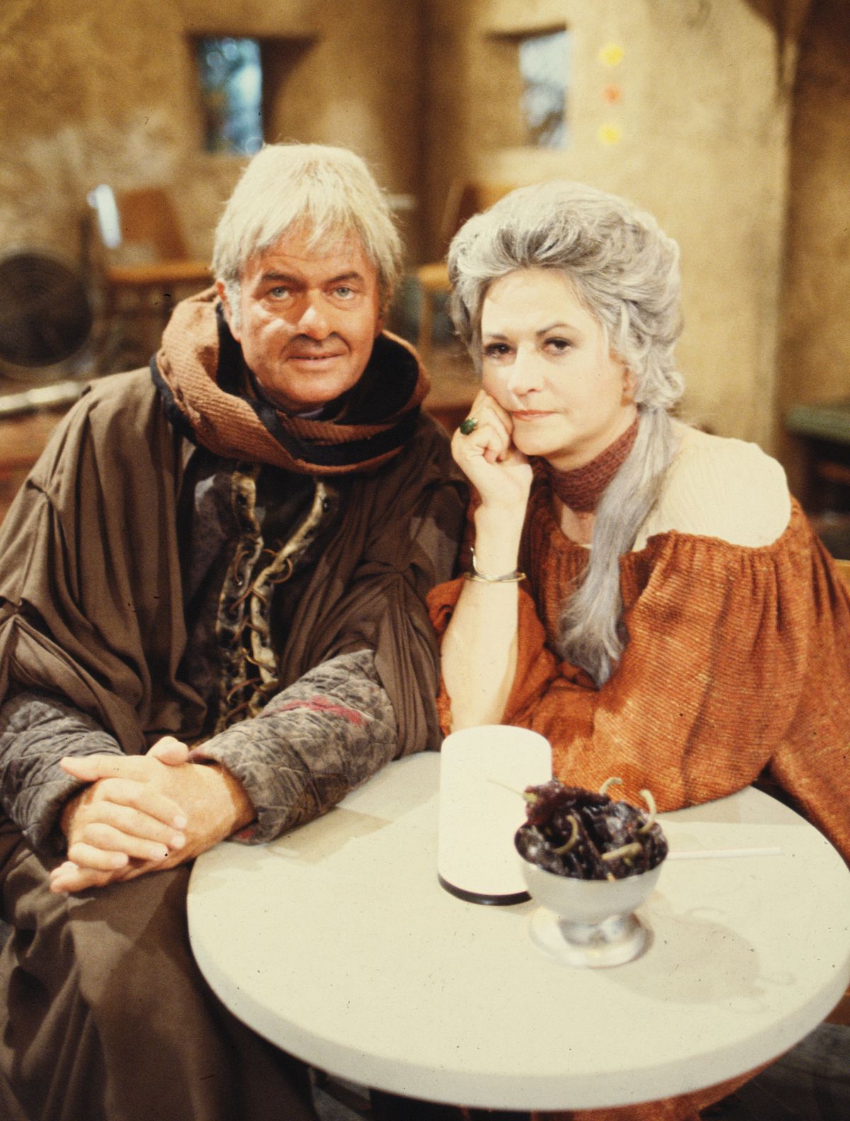 Art Carney and Bea Arthur sit together in their Star Wars costumes, looking at the camera, in a posed publicity photo for 1978’s The Star Wars Holiday Special