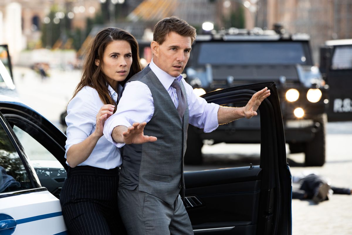 (LR) Hayley Atwell y Tom Cruise saliendo de un auto con las manos levantadas en Misión Imposible: Dead Reckoning Part One.