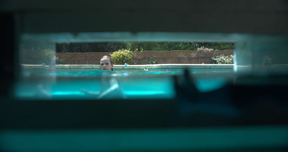 Otrok gleda proti skimerju bazena, ki ga vidimo iz perspektive skimerja v Nočnem kopanju