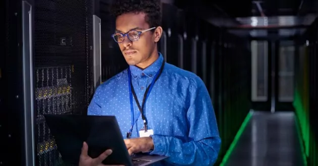 Fokusert IT-tekniker bruker bærbar PC i mørkt serverrom