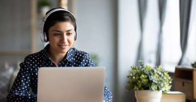 Person wearing headphones smiling at laptop