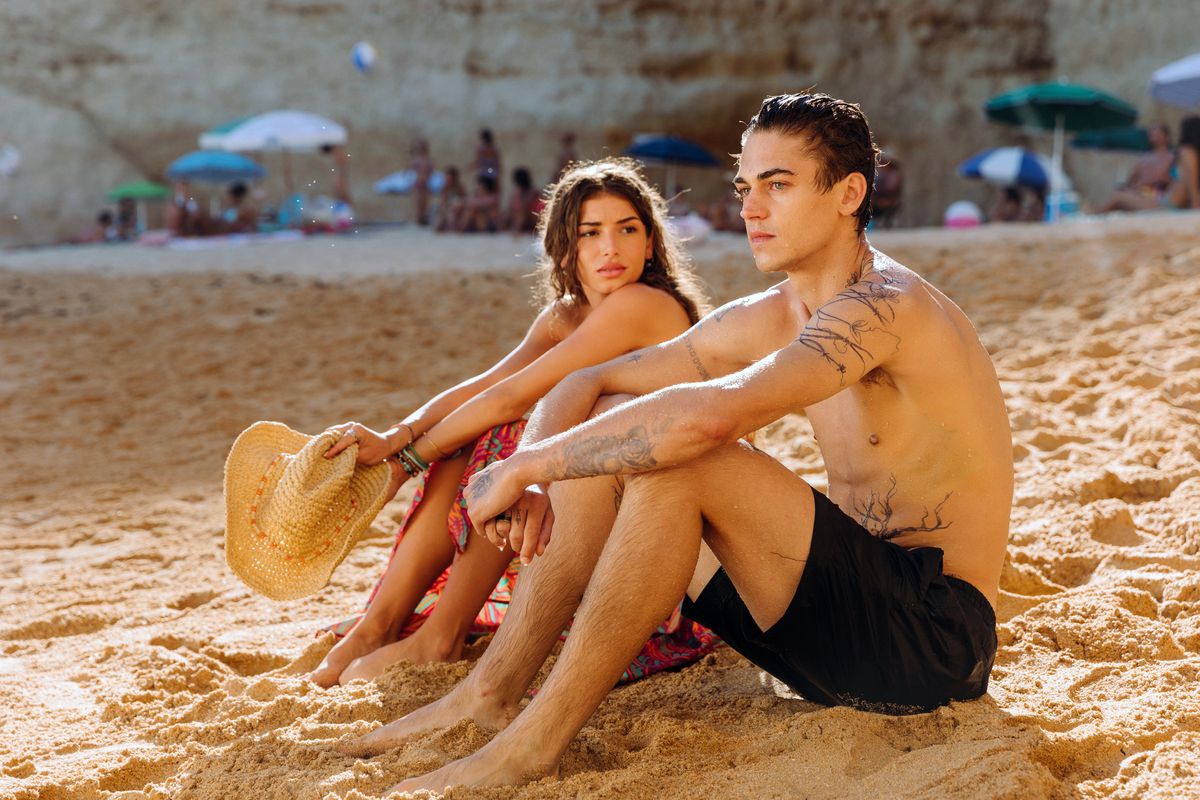 (L-R) Mimi Keene e Hero Fiennes Tiffin seduti su una spiaggia in Dopo tutto.
