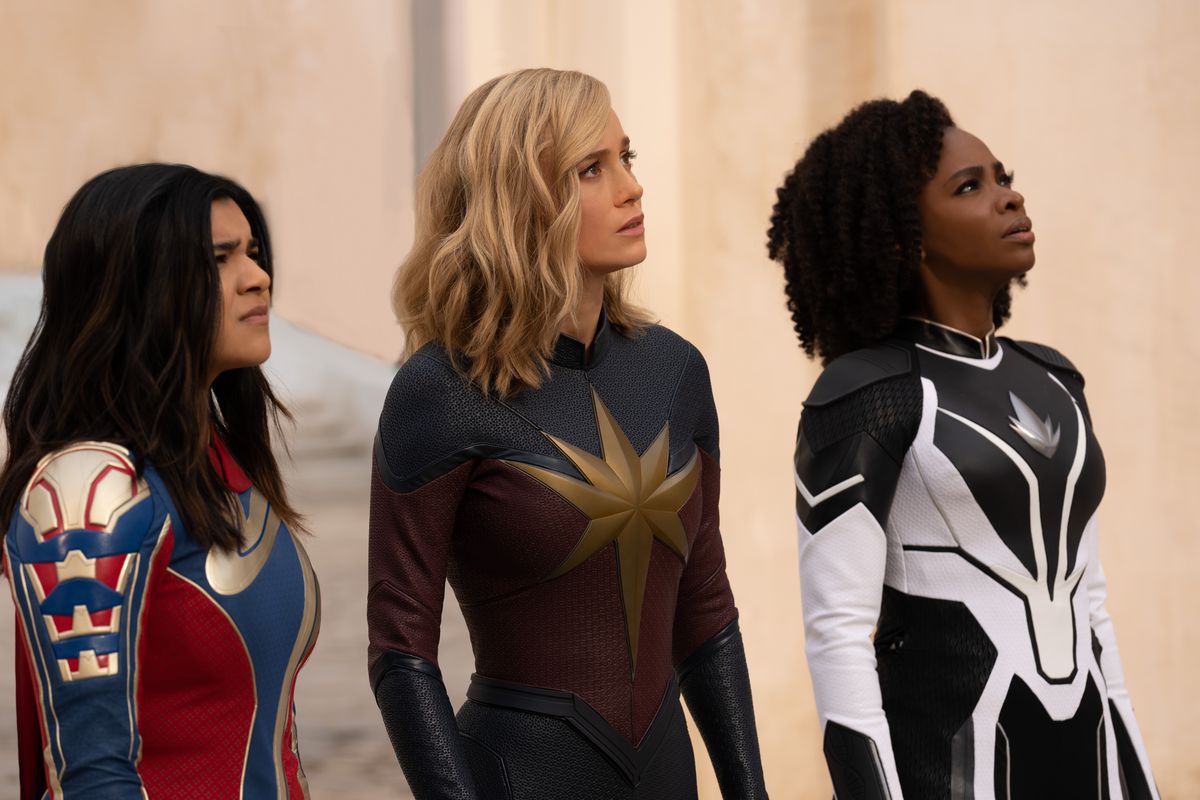Η Iman Vellani ως Ms. Marvel/Kamala Khan, η Brie Larson ως Captain Marvel/Carol Danvers και η Teyonah Parris ως Captain Monica Rambeau στέκονται μαζί με κοστούμια, κοιτάζοντας ψηλά, στην ταινία Marvel Cinematic Universe The Marvels