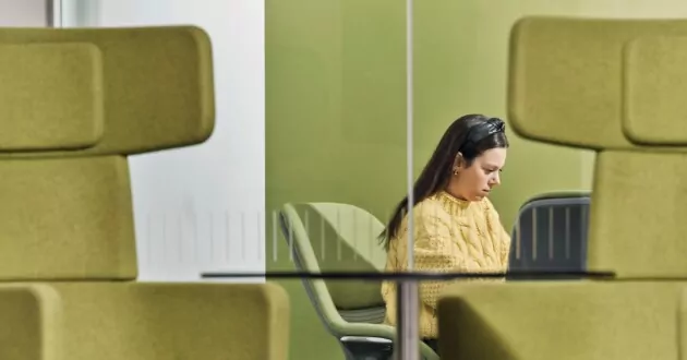 Orang yang menggunakan laptop di antara kursi hijau di IBM