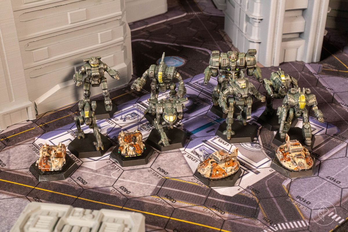 Eight BattleMechs lined up in a city setting behind four ground vehicles: two tanks and two hovercraft.
