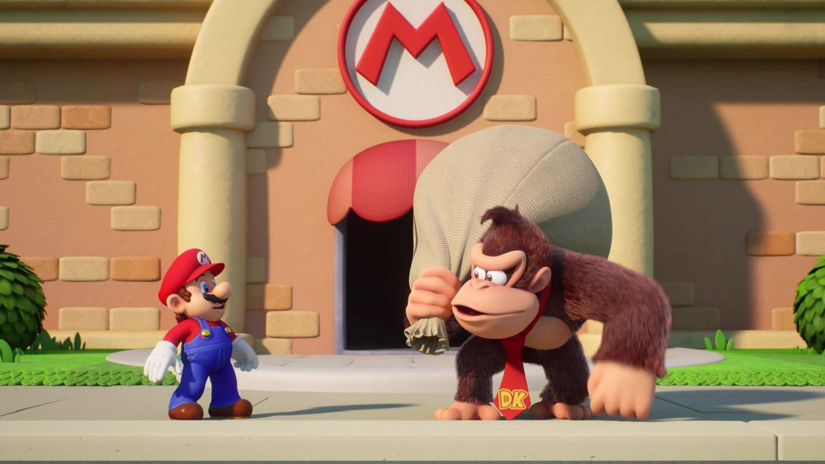 Mario blickt Donkey Kong fragend an, der einen großen Sack über der Schulter trägt, während er vor einem Gebäude mit Marios Logo darauf steht. Ehrlich gesagt sieht es so aus, als hätte Donkey Kong gerade Mario ausgeraubt. Es ist ein Screencap von Mario vs. Donkey Kong.