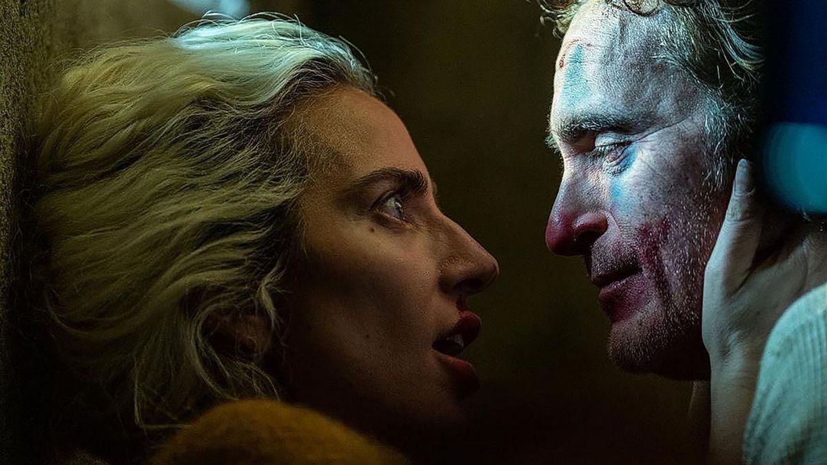 Lady Gaga, as Harley Quinn, looks into Joaquin Phoenix’s Jokers eyes as they hold each other in Joker: Folie à Deux 