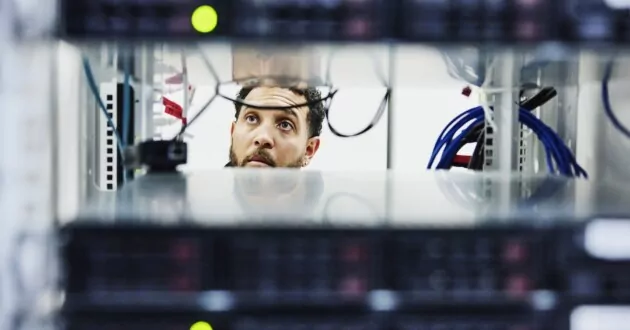 Людина дивиться через серверну стійку центру обробки даних