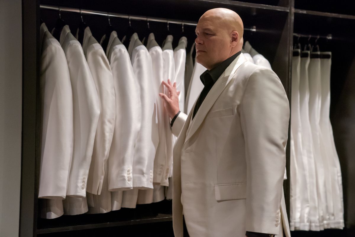 Vincent D’Onofrio as Wilson Fisk in Daredevil S3 walking past a line of white suits and feeling them.