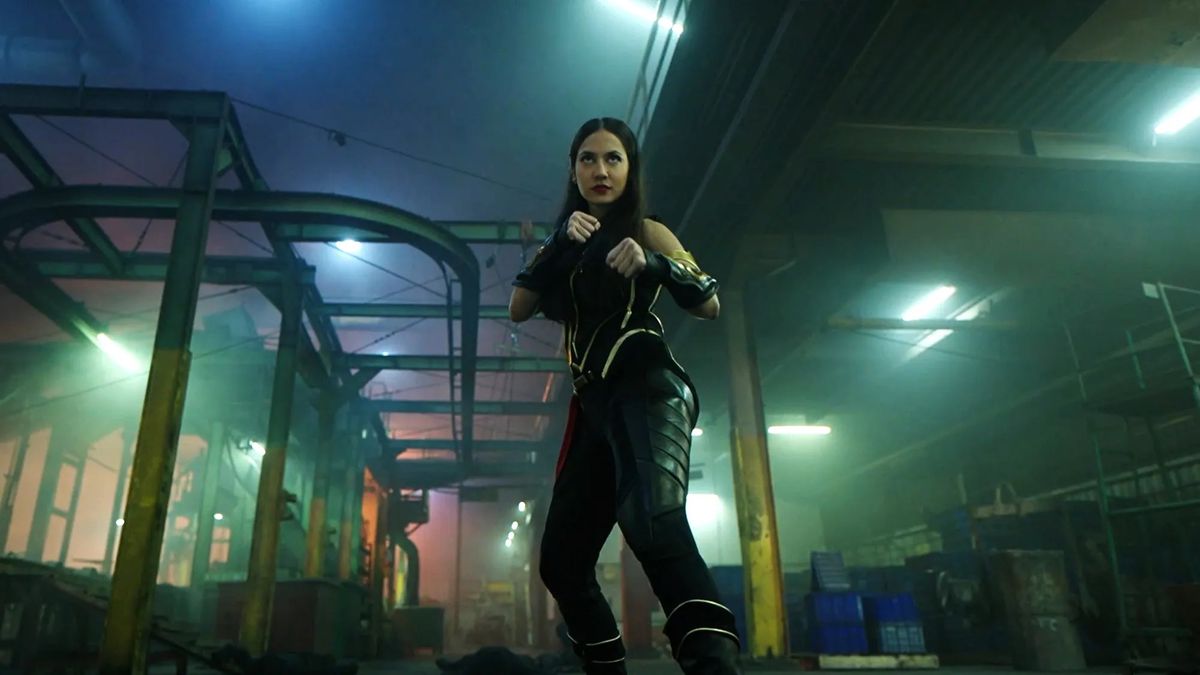 スーパーヒーローの衣装を着た若い女性、シュリ・アシが拳を振り上げてシュリ・アシで戦う